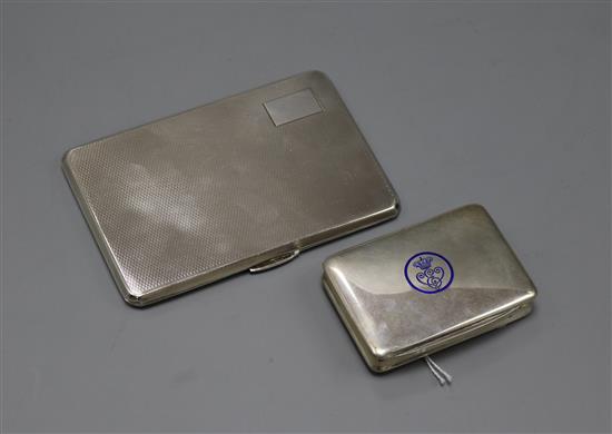 An engine-turned silver cigarette case and a small Continental cigarette case with blue enamel insignia.